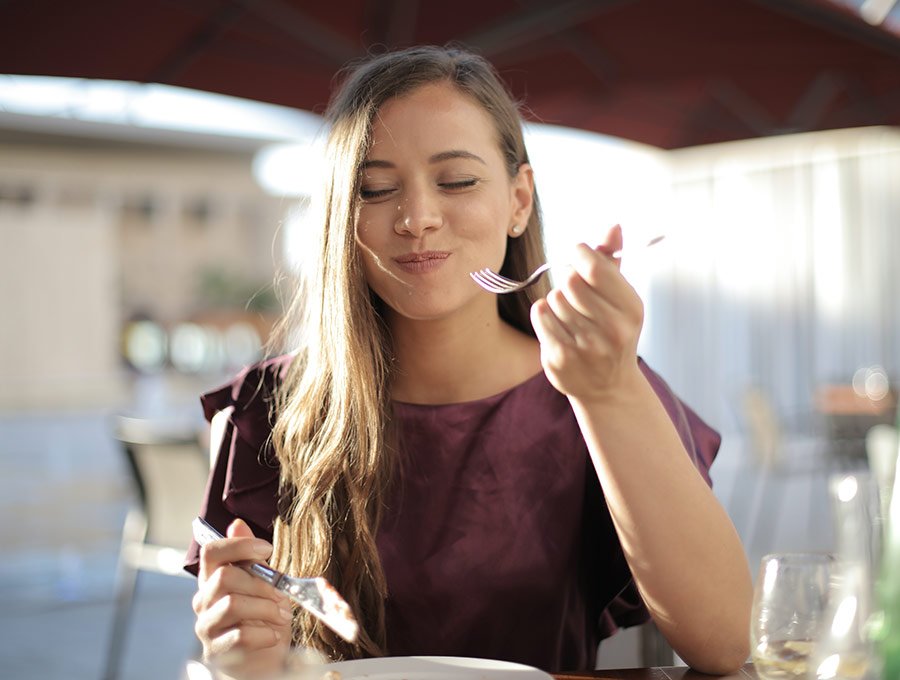 Chica comiendo un delicioso plato de albóndigas en la terraza de un bar.