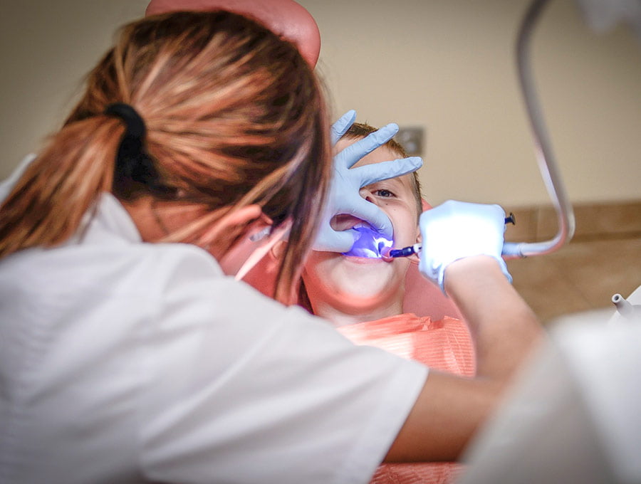 Una dentista revisando que los dientes del paciente están sanos.