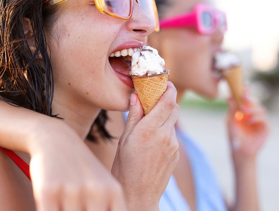 Dos amigas comen helado sin sufrir molestia de hipersensibilidad dental.