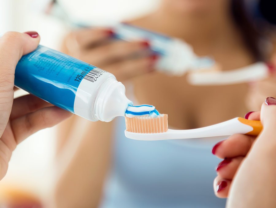 Mujer utiliza pasta de dientes en su cepillo de cerdas duras.
