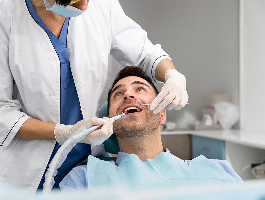 Dentista preparando la boca del paciente para quitarle una muela picada.