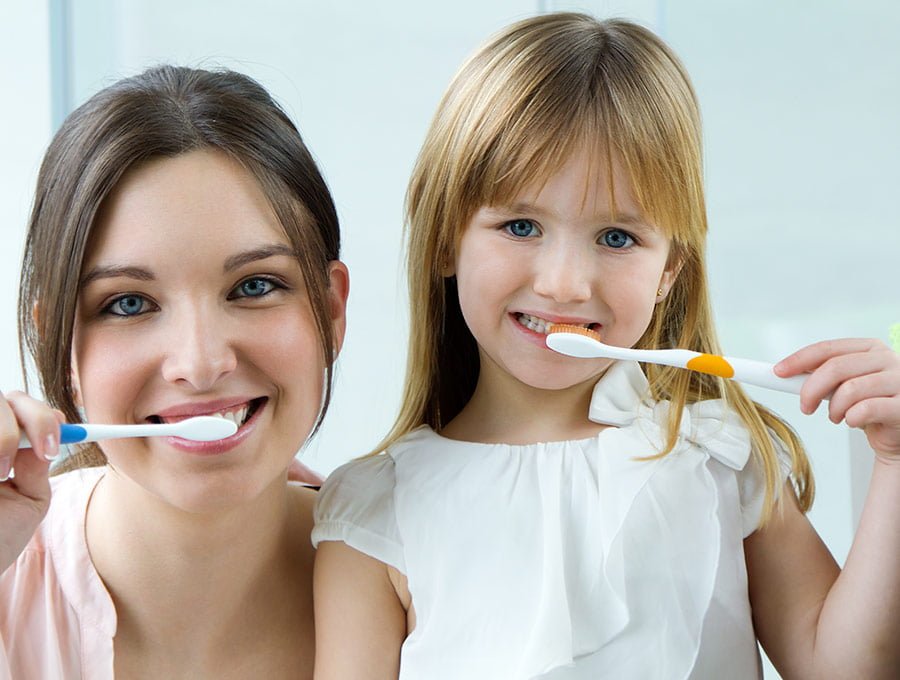 Madre e hija se limpian los dientes en el baño.