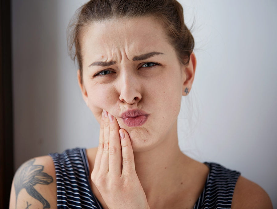Mujer tiene un poco de dolor en la zona inferior de la boca tras una intervención odontológica.