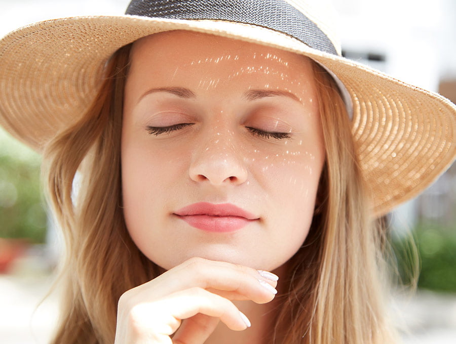 Mujer con sombrero de paja disfrutando del día soleado y cargándose de vitamina D.