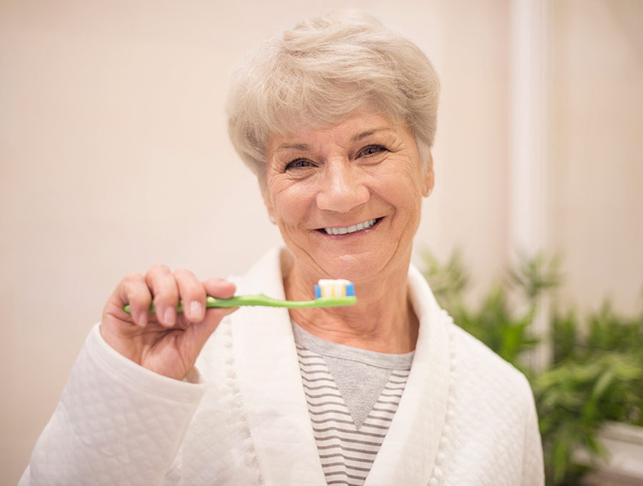 Mujer mayor a punto de cepillarse los dientes.