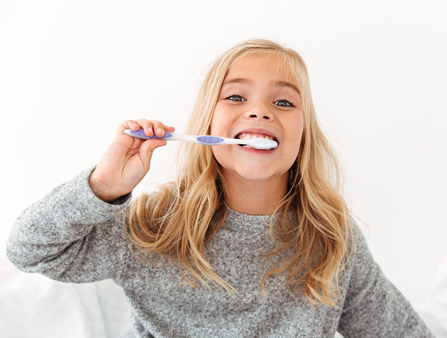 Niña pequeña se cepilla los dientes con un cepillo dental de cerdas suaves.