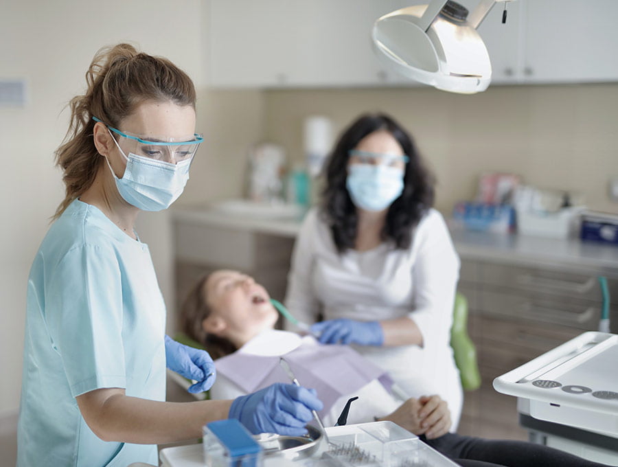 Dentista revisando la boca de una paciente en la consulta.