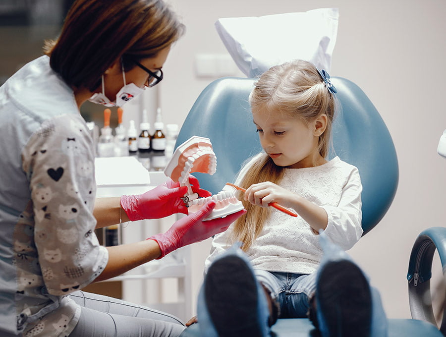 La dentista explica cómo debe cepillarse los dientes después de la endodoncia a esta niña pequeña.