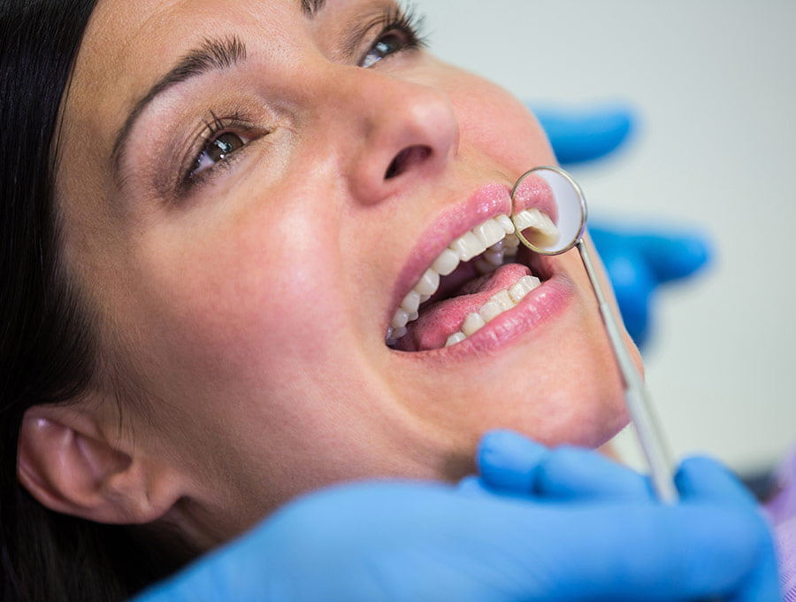 Dentista revisa los dientes de una paciente tras el blanqueamiento dental.