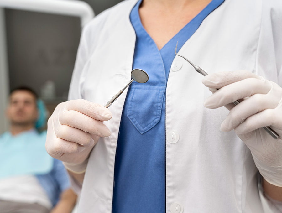 Dentista coge sus herramientas para empezar el chequeo de un paciente.