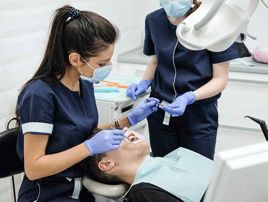 Dentistas trabajando en la boca de un paciente con caries dental.