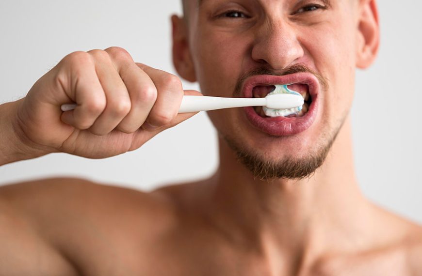 Este hombre se está limpiando los dientes con pasta dental y un poco de bicarbonato.