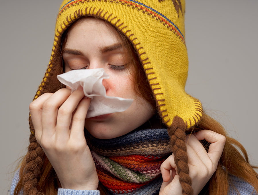 Chica se limpia la nariz con pañuelo porque tiene gripe.