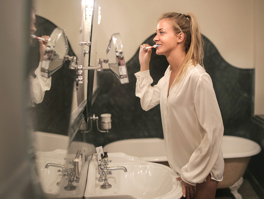 Esta chica se está limpiando los dientes delante del espejo, ha usado bicarbonato y dentífrico.