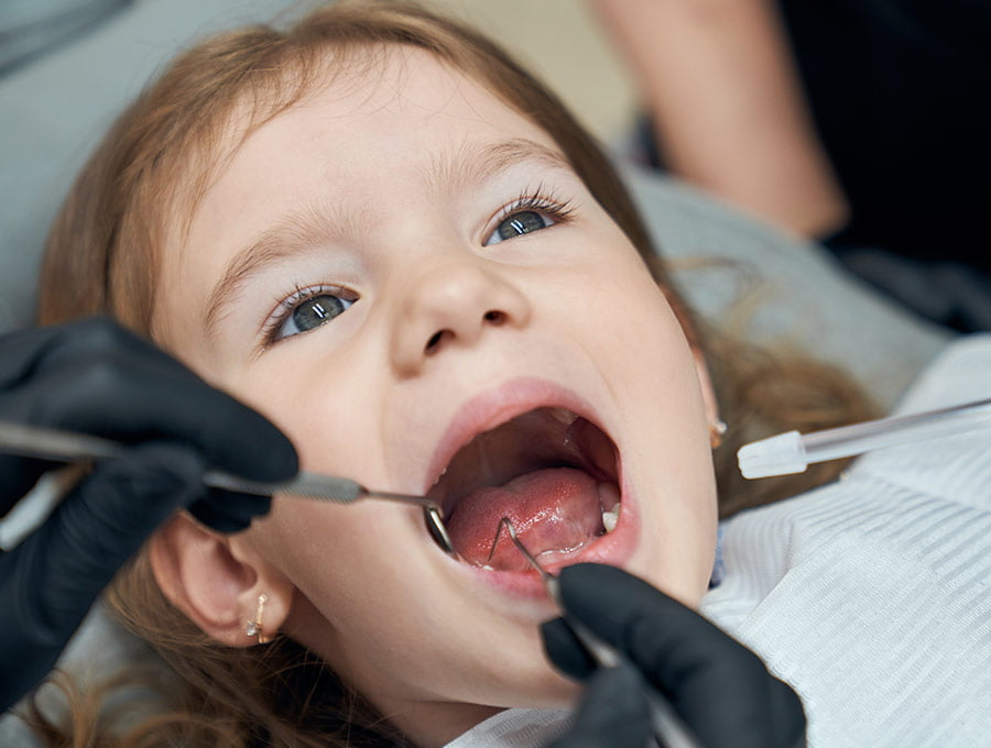 Dentista revisa bien la boca de su pequeña paciente de 4 años.