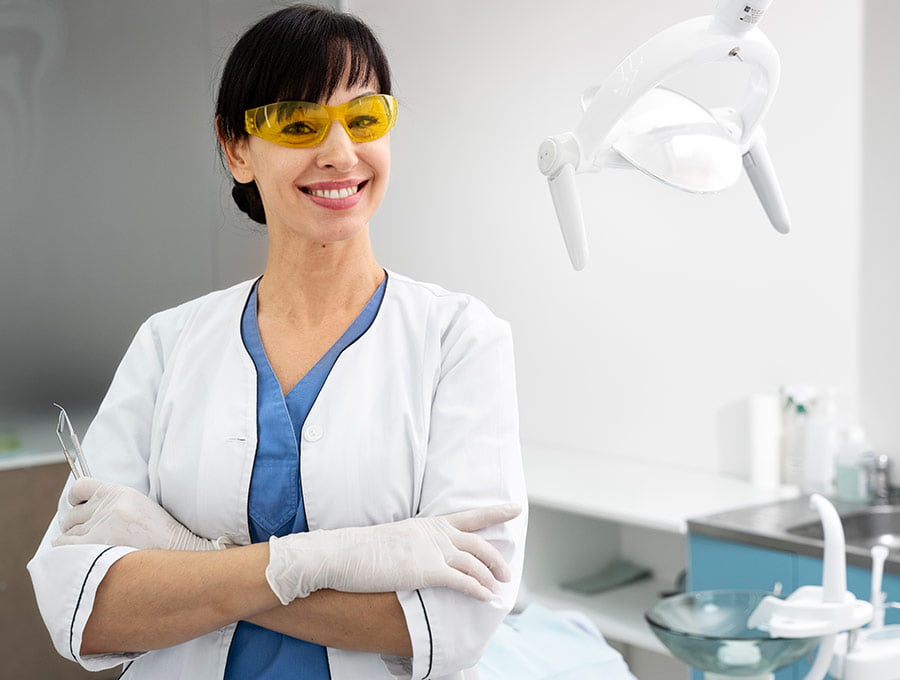 Dentista con gafas de color amarillo, al lado de sus herramientas de trabajo.